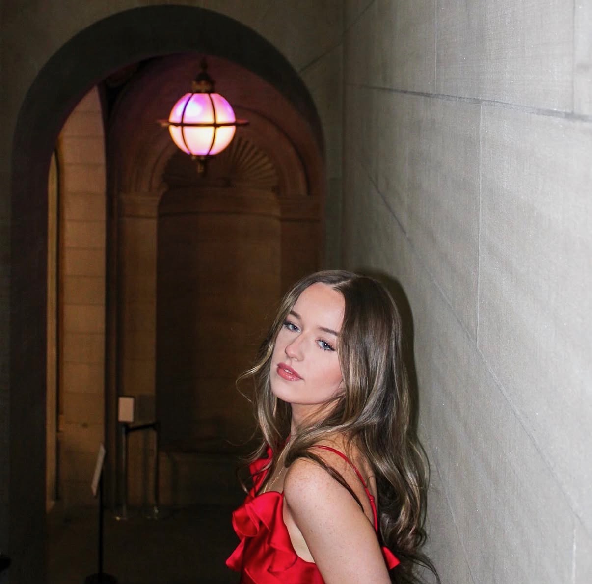 Evening portrait in a red dress beneath a glowing lantern