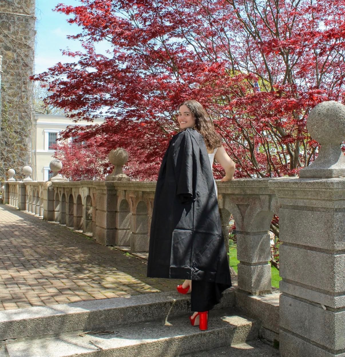Full length graduation portrait beneath a Japanese maple